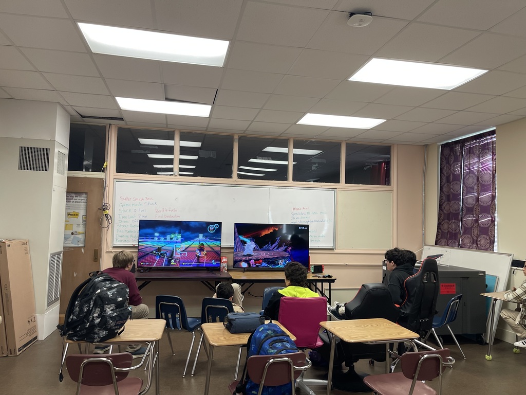 Students are gathered around two tvs playing Mario Kart.