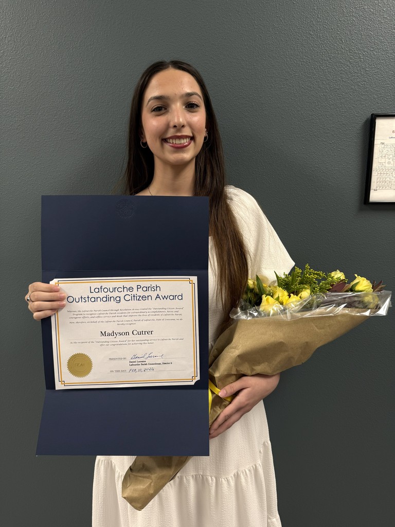 Madyson Cutrer smiles while holding a bouquet of yellow flowers and the Lafourche Parish Outstanding Citizen Award certificate she received on February 10, 2026.