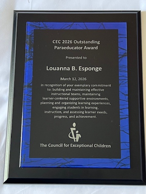 Here is the ADA-compliant alt text for the third photo, ensuring all text from the award is accessible.  Alt Text A close-up of a commemorative plaque with a blue glass border featuring a subtle black branch pattern. The center of the plaque is black with silver text that reads: "CEC 2026 Outstanding Paraeducator Award, Presented to Louanna B. Esponge, March 12, 2026. In recognition of your exemplary commitment to: building and maintaining effective instructional teams, maintaining learner-centered supportive environments, planning and organizing learning experiences, engaging students in learning, instruction, and assessing learner needs, progress, and achievement." At the bottom is the logo for The Council for Exceptional Children.