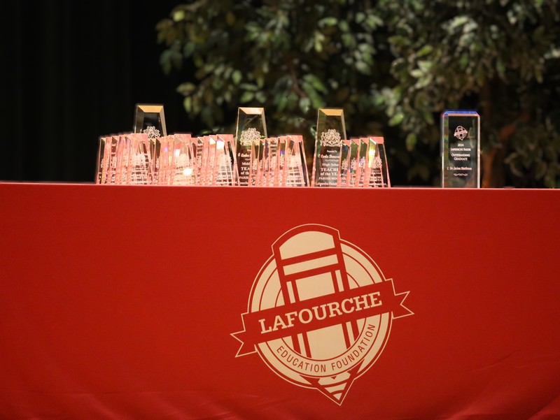 Trophies sit on a table with a red tablecloth bearing the LEF logo.