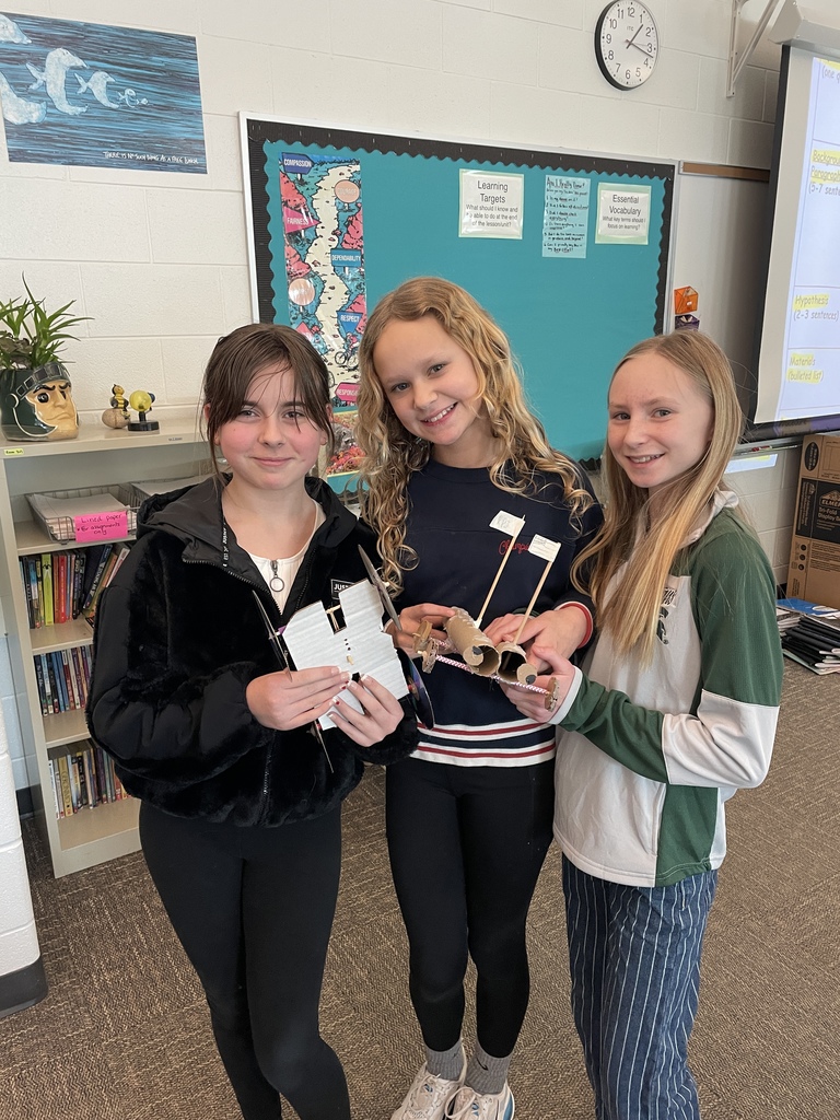 Girls holding a rubber band car they made in STEM