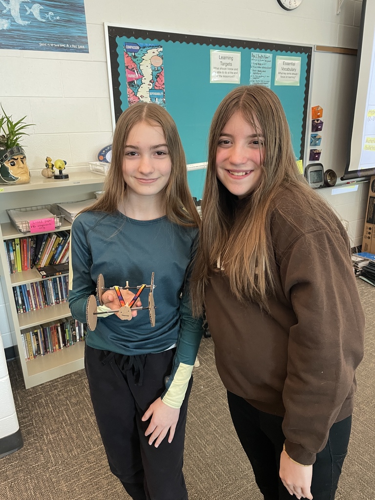 Girls holding a rubber band car they made in STEM