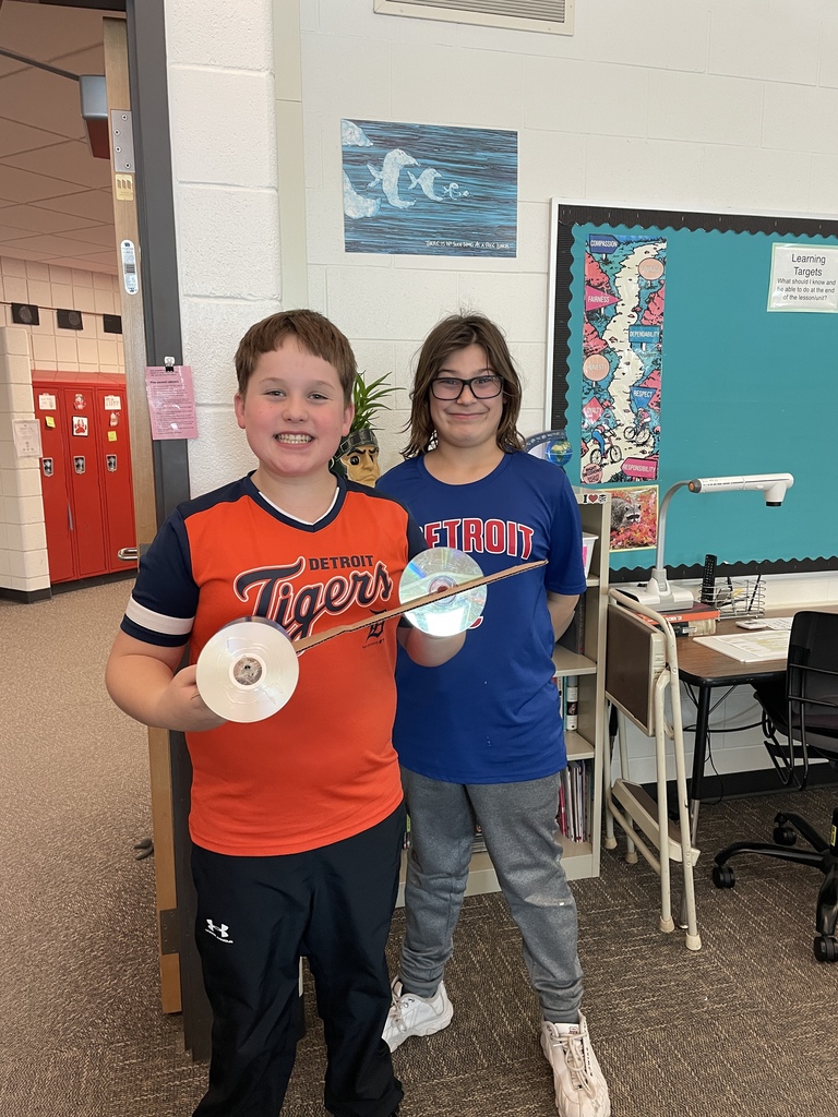 Boys holding a rubber band car they made in STEM. 