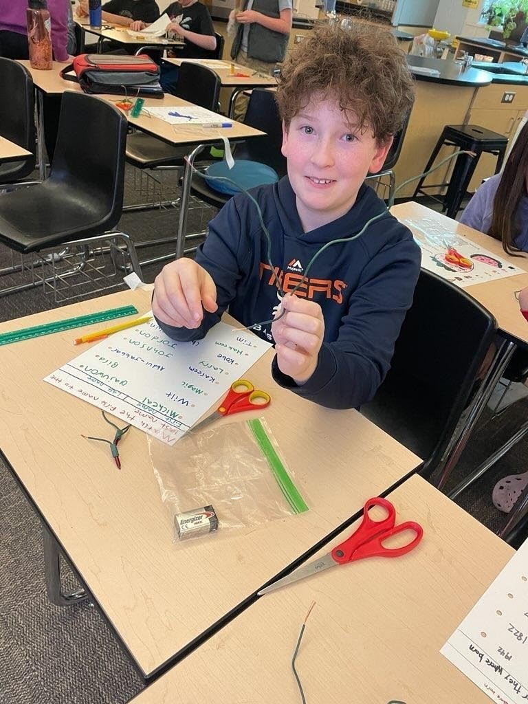 student at desk in classroom with STEM supplies