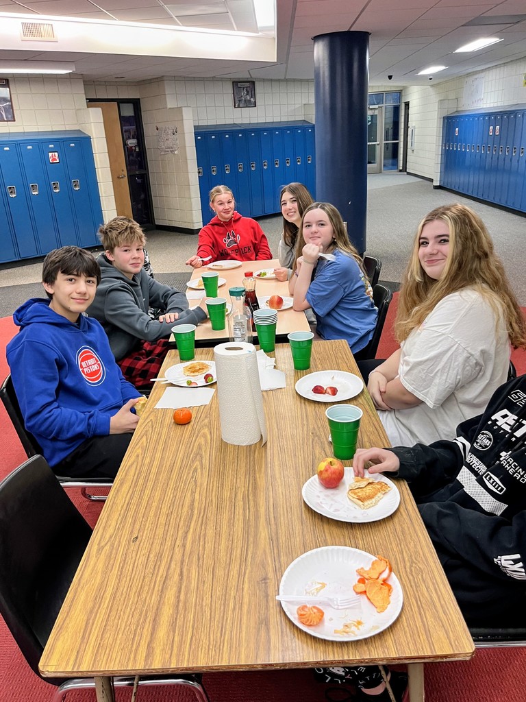 Students eating breakfast at a table in the hallway