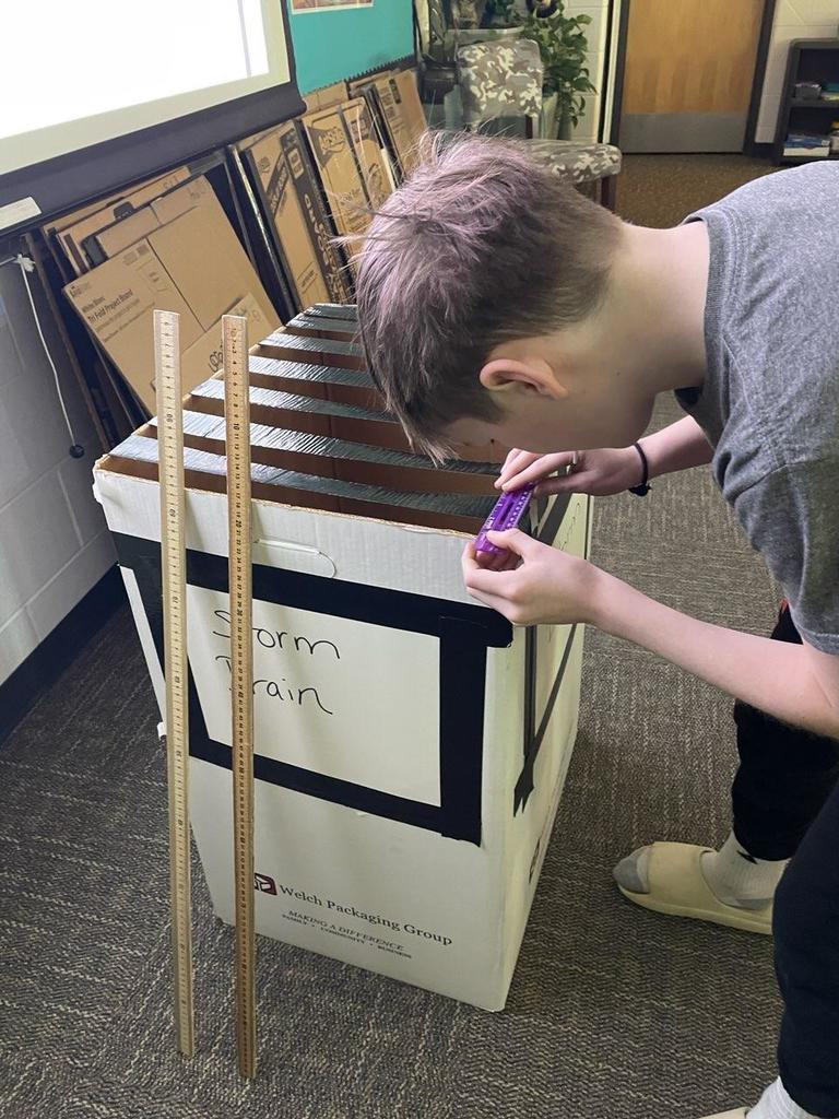 Student in STEM class helping to get keys out of a faux storm drain