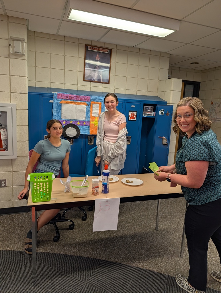Kids behind a table in a school selling food  for their school project