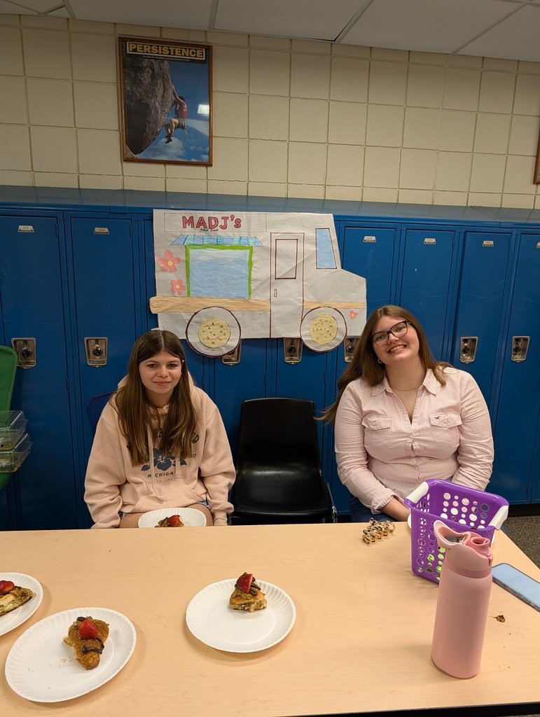 Kids behind a table in a school selling food  for their school project