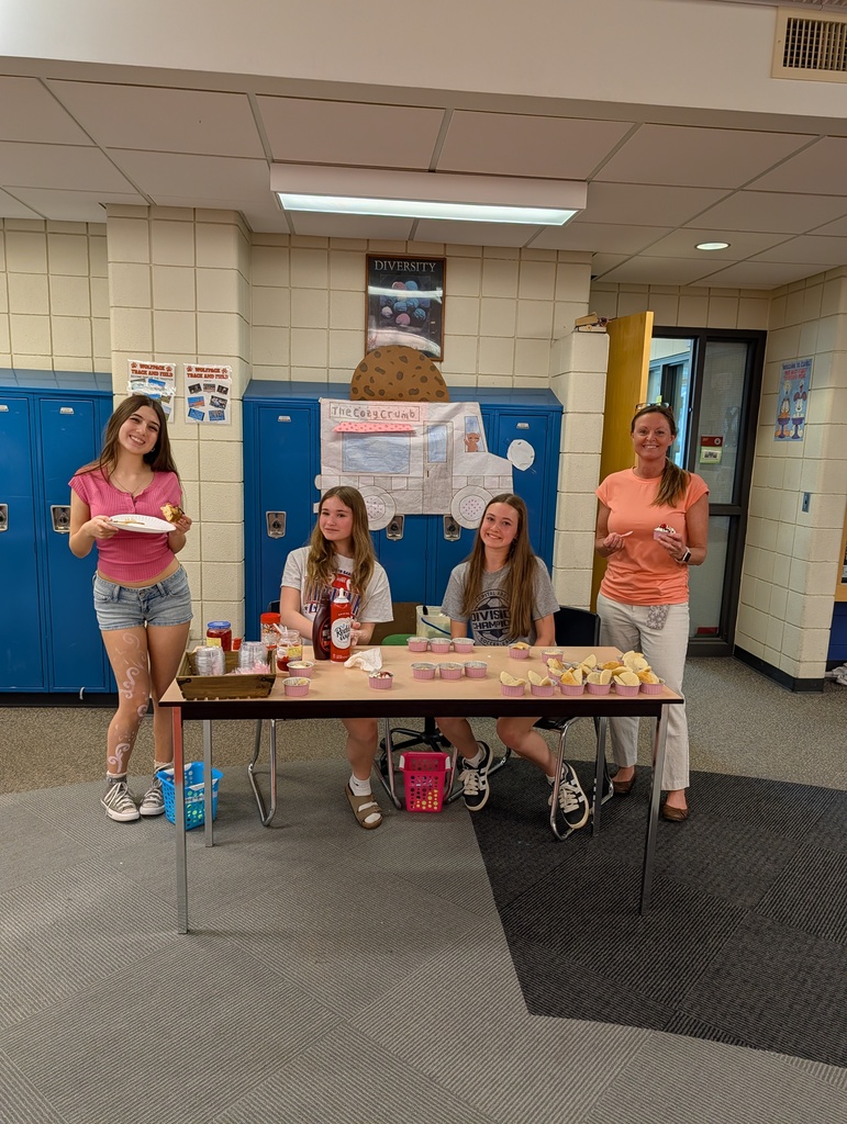 Kids behind a table in a school selling food  for their school project