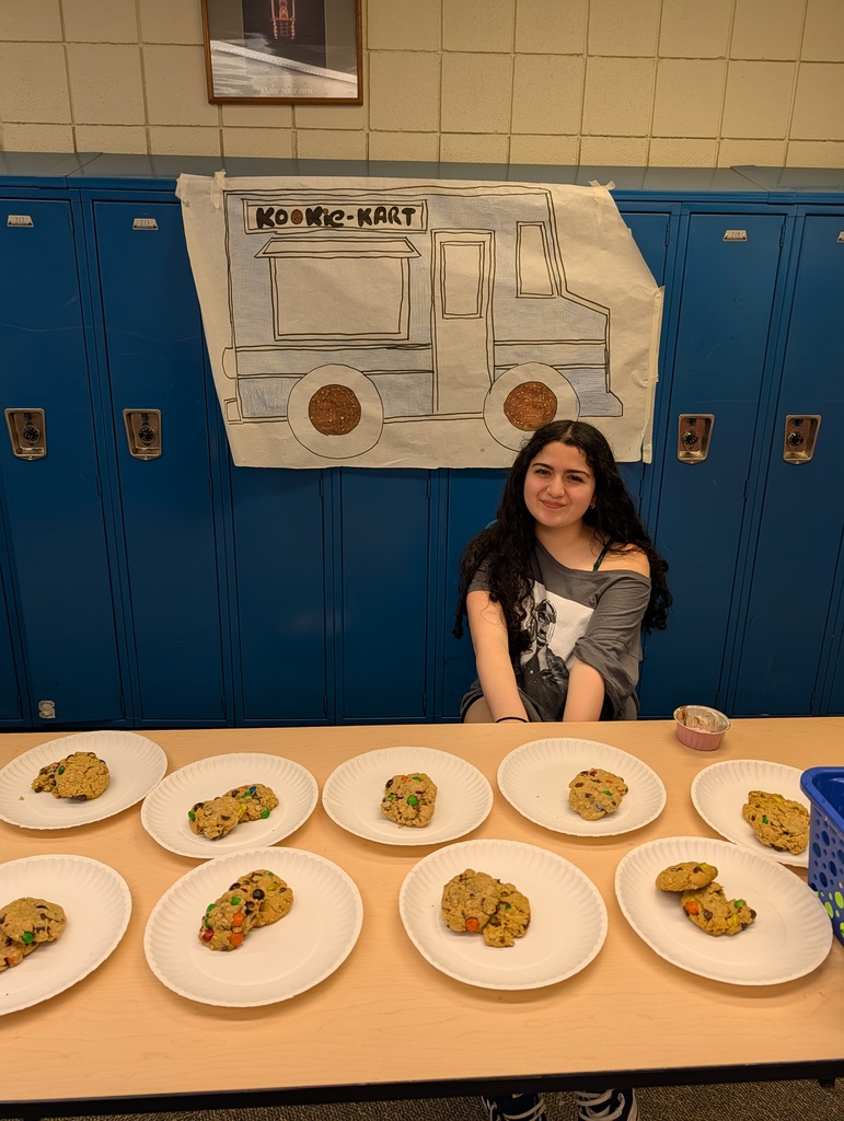 Kids behind a table in a school selling food  for their school project