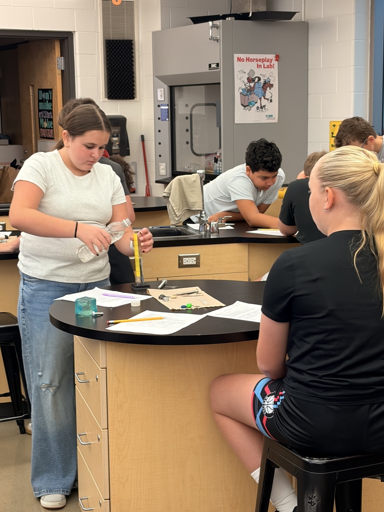 Students measuring fluid in science lab