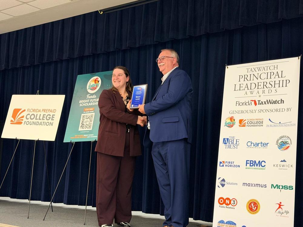 Wes Locke on stage being presented a plaque.