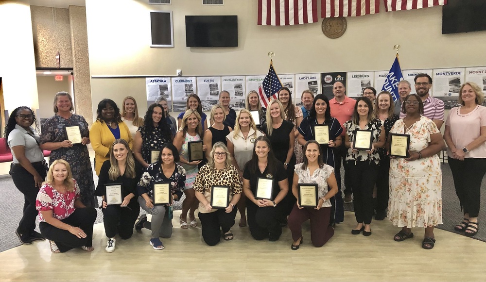 Group of teachers holding plaques.