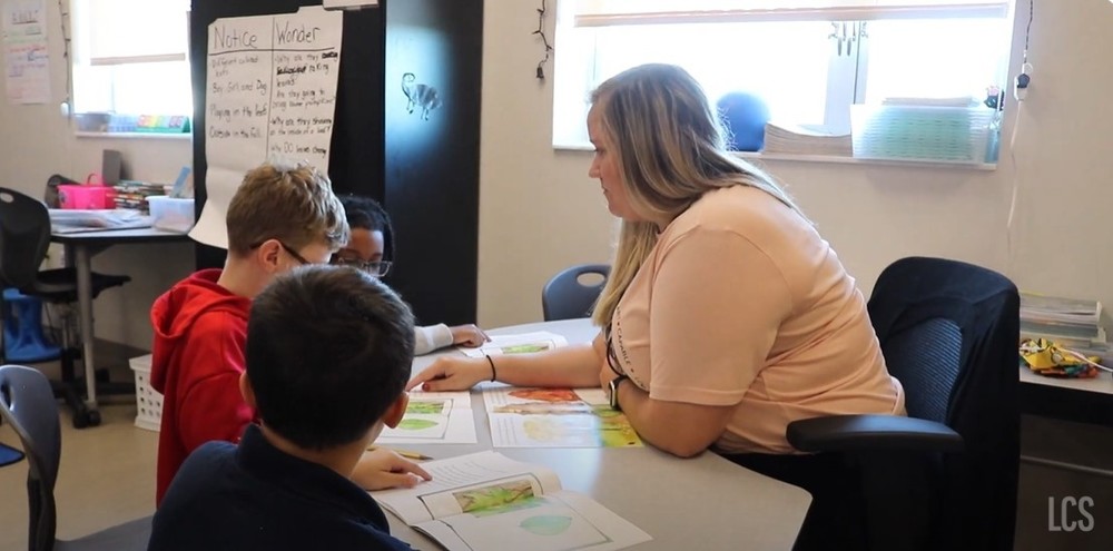 Teacher working with three elementary students on one side of a semi-circle desk
