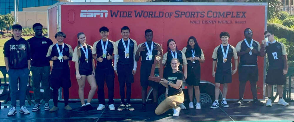 Student athletes posed and smiling. Some are wearing medals. One is holding a trophy. Wording in background says, "ESPN Wide World of Sports Complex, Walt Disney World Resort"