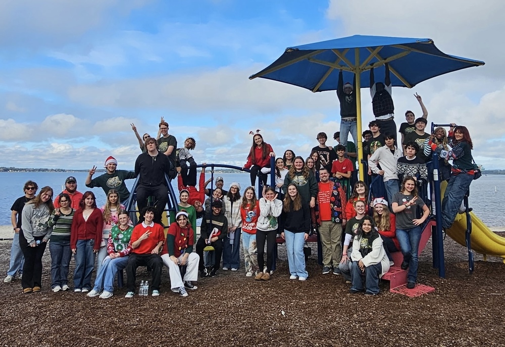 Choir posed casually in front of Lake on playground
