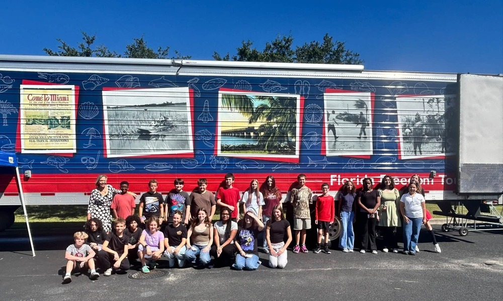 Group of students posed outside a large truck with large photographic images of Florida scenes