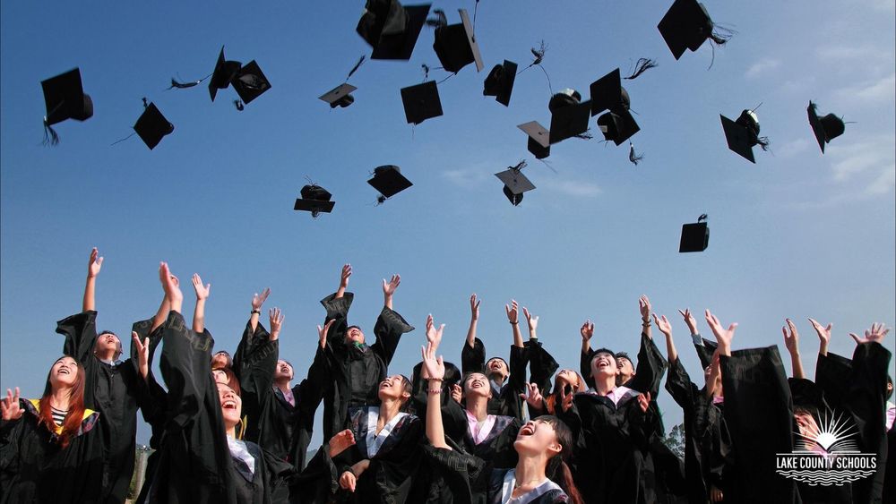 Stock image of students in graduation robes throwing their graduation caps up in the air