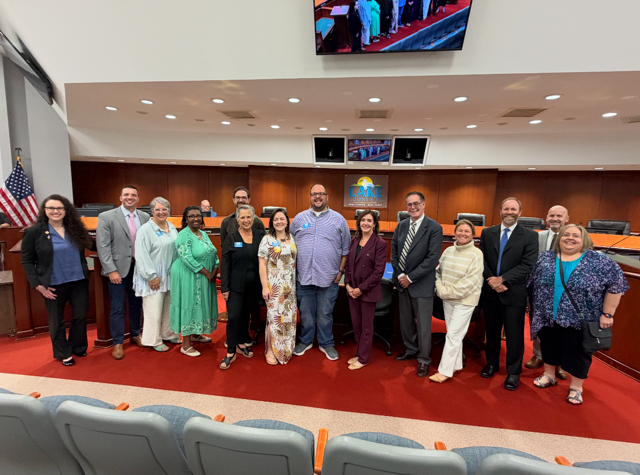 Group of adults standing in front of dais at the Lake County Commission chambers