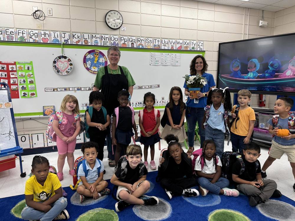 Young student posed seated on carpet and standing with backpacks