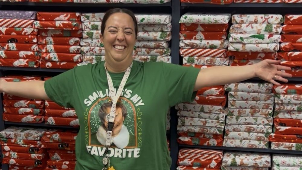 Meagan Dewitz standing in front of shelves of wrapped Christmas gifts