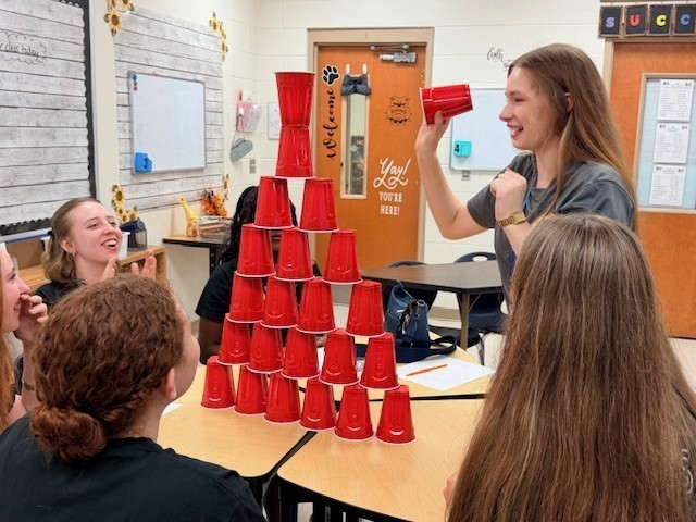 Teens stacking red solo cups into pyramid