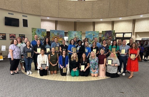 Group of elementary principal posed holding plaques