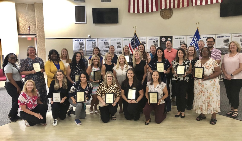 Group of teachers holding plaques.