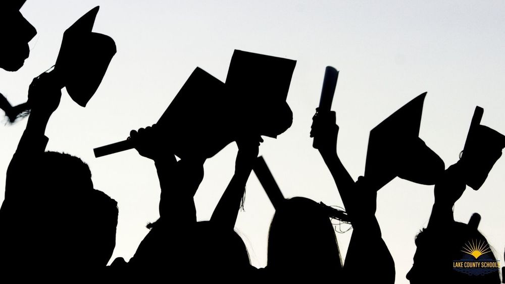 Silhoutte photo of graduates with caps and diplomas raised in the air