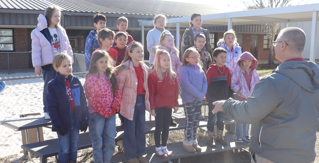 students on risers outside singing