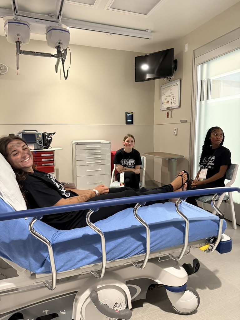 Student enactor poses in hospital bed with dark smudges on her face and arms