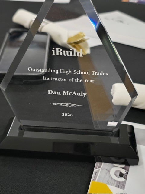 Picture of glass trophy that reads, "iBuild -Outstanding High School Trades Instructor of te Year, Dan McAuly, 2026"