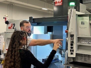 Teacher and student pointing at a large computer screen