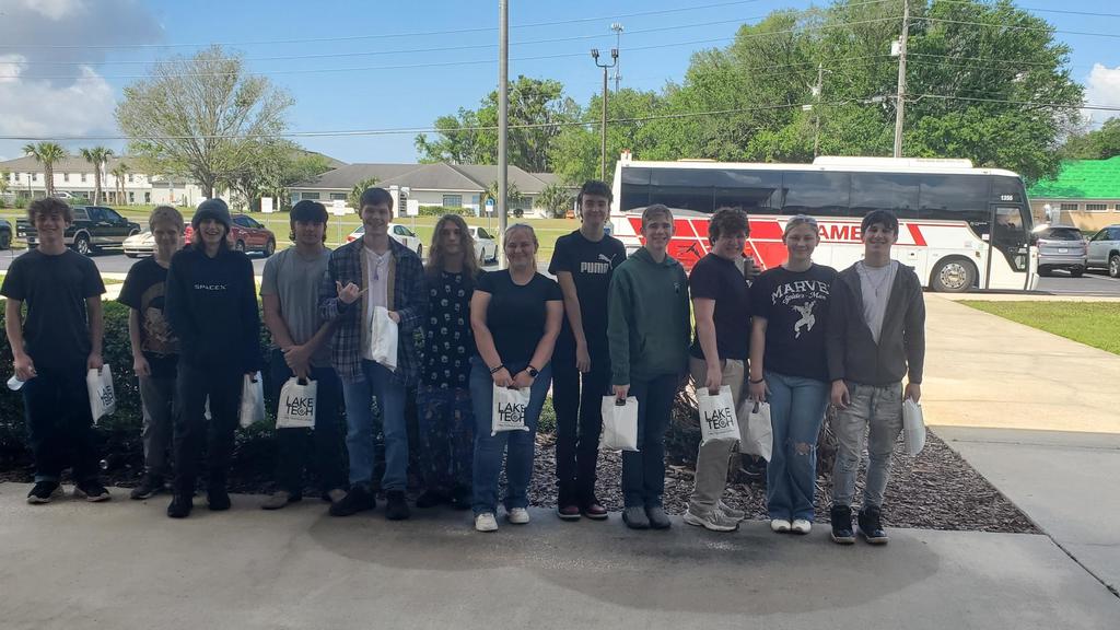 High school students standing posed outside in front of a chartered bus
