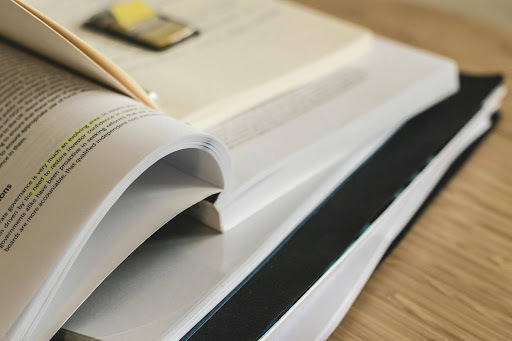 Stock image of open paperback book with yellow sticky tabs on top of the open page. 