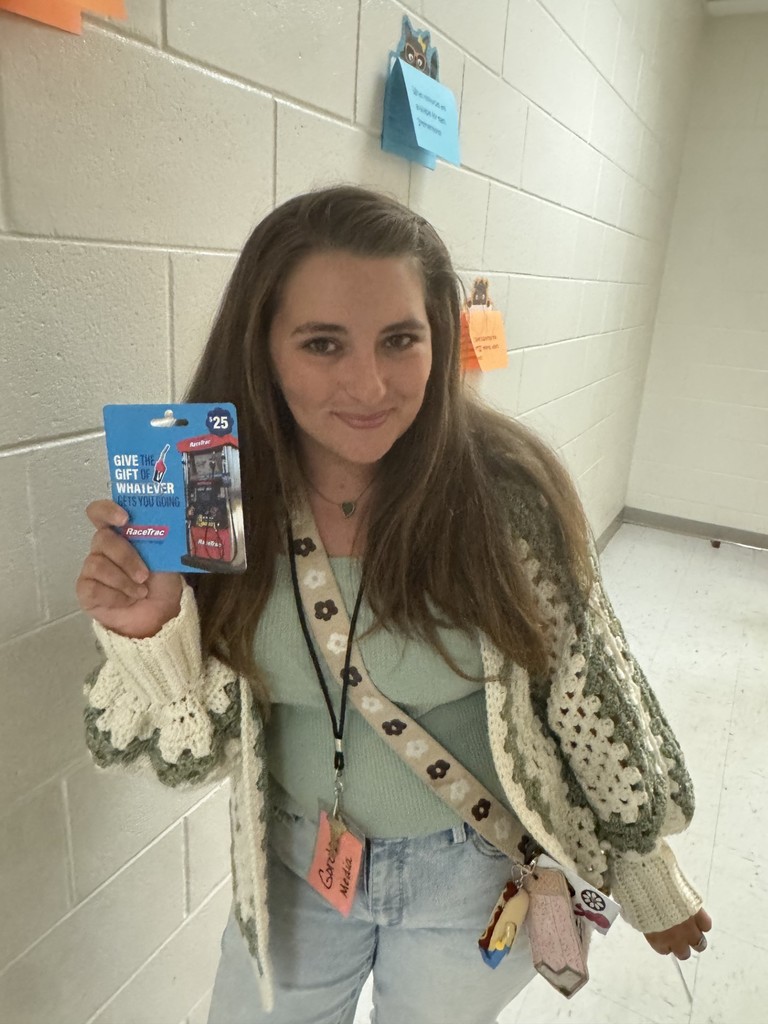 Smiling woman holding up a gift card that she won in Name That Tune trivia game for Teacher Appreciation! 