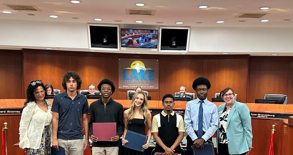5 students posed with two adults. Students are holding certificates.