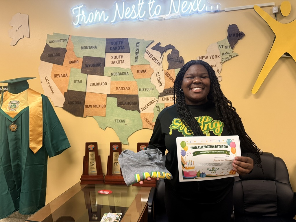 Person holding a certificate, smiling in front of a map, wearing a black shirt and a graduation robe.