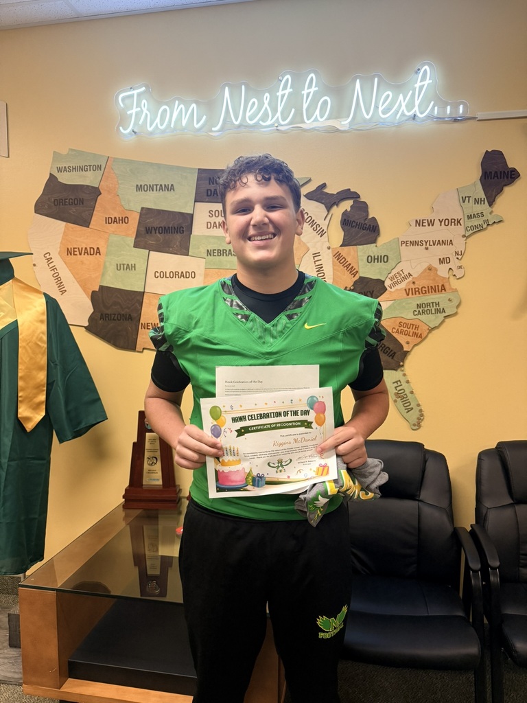 A young man stands with a certificate in a room with a yellow wall and a map of the United States.