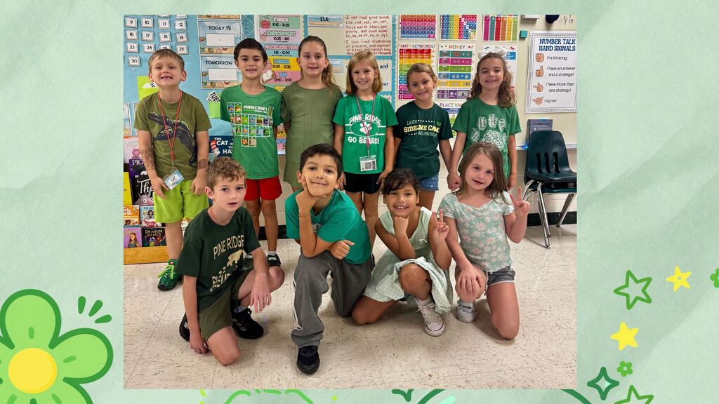 Children in green shirts pose in a classroom with green borders. Some smile and make peace signs.