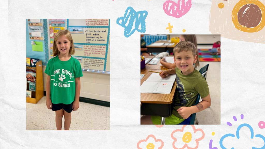 Two children in classroom setting, one stands with a green shirt, other sits at a desk, both smiling.
