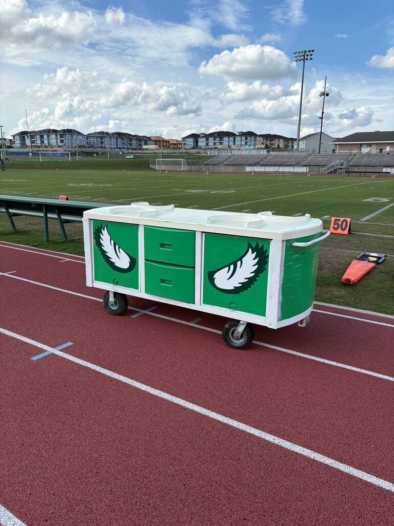 A red track with a green cart featuring eagle designs. Buildings are in the distance.