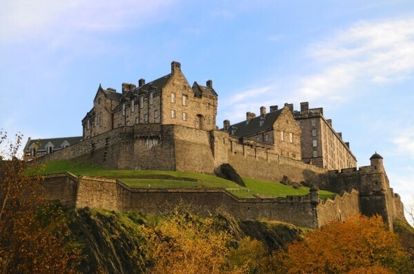 A castle with multiple towers on a hill, surrounded by trees with yellow and orange leaves.