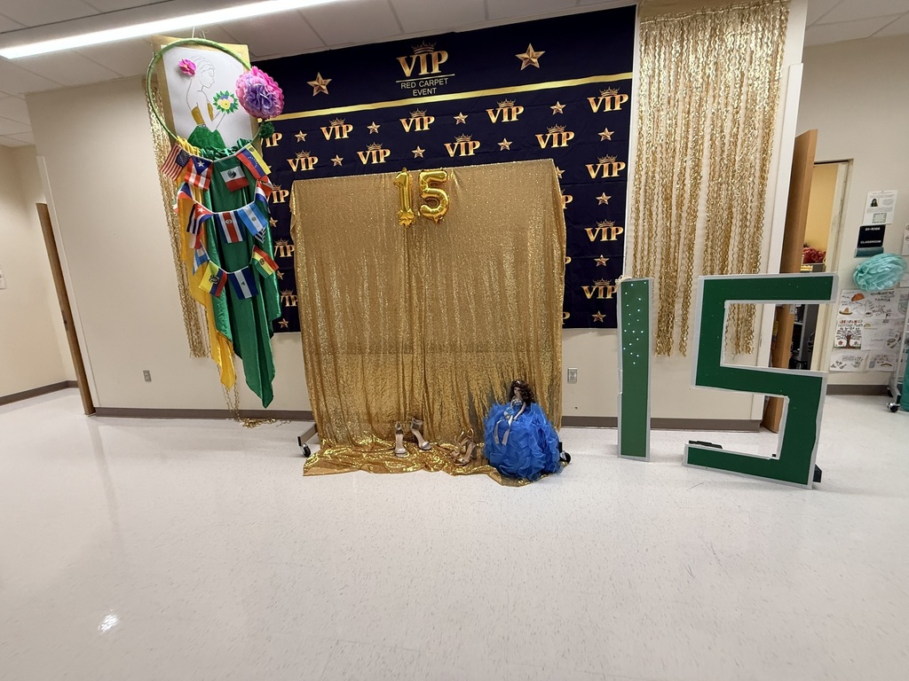 A decorated room with a "VIP" backdrop, gold curtain, and "15" letters. A doll and blue bag are on the floor.