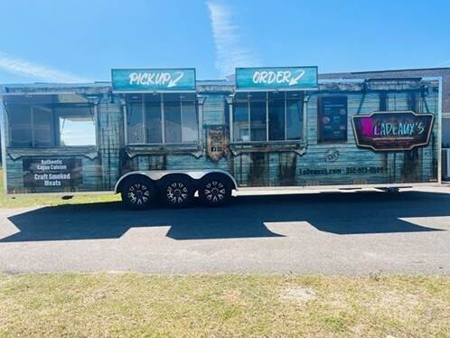 A food truck with signs saying "PICKUP" and "ORDER" parked on the side of the road.
