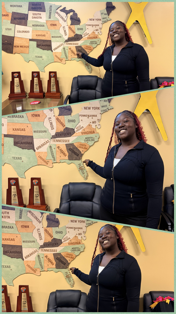 Three women with braids and black jackets in front of a map with three trophies displayed.