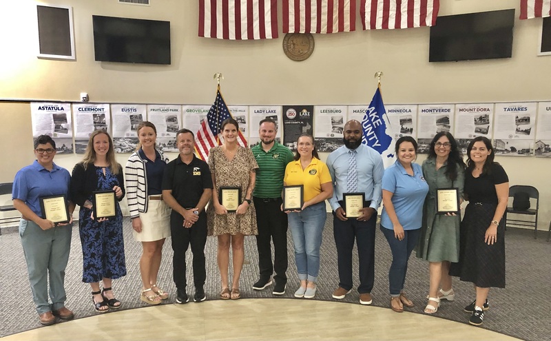 Teachers standing holding plaques
