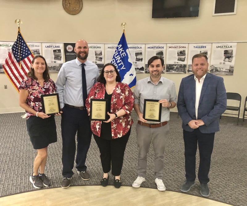 Teachers standing holding plaques