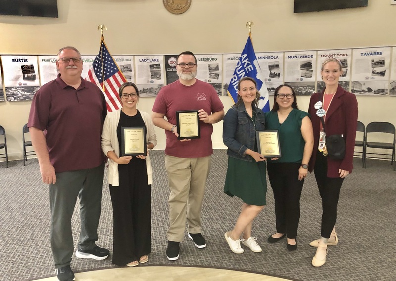 Teachers standing holding plaques