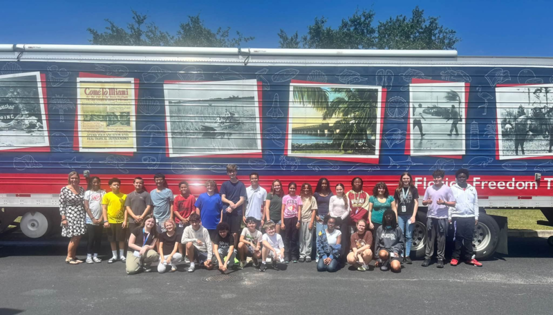 Group of students posed outside a large truck with large photographic images of Florida scenes